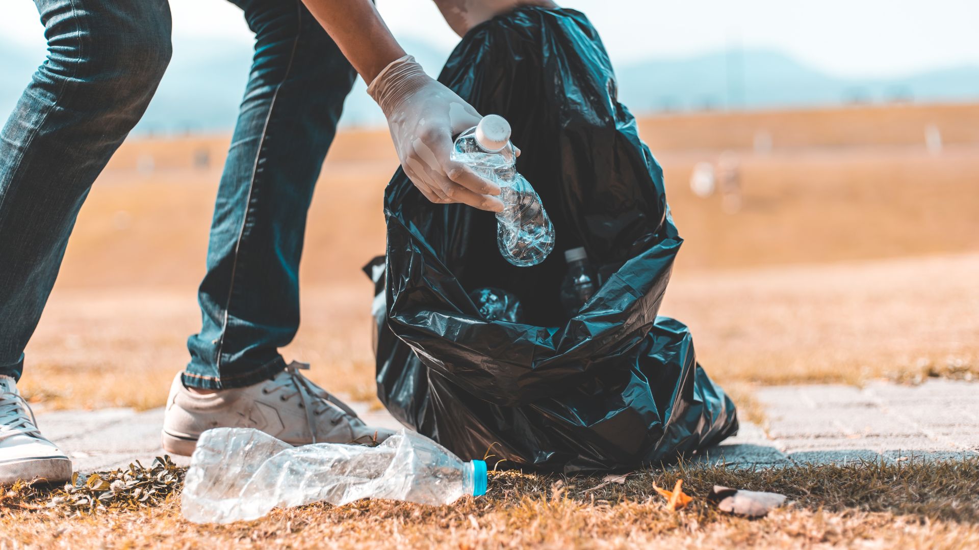 Person picking up a plastic bottle. 