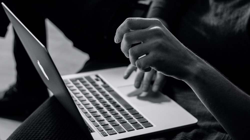 black white photo of someone holding a macbook