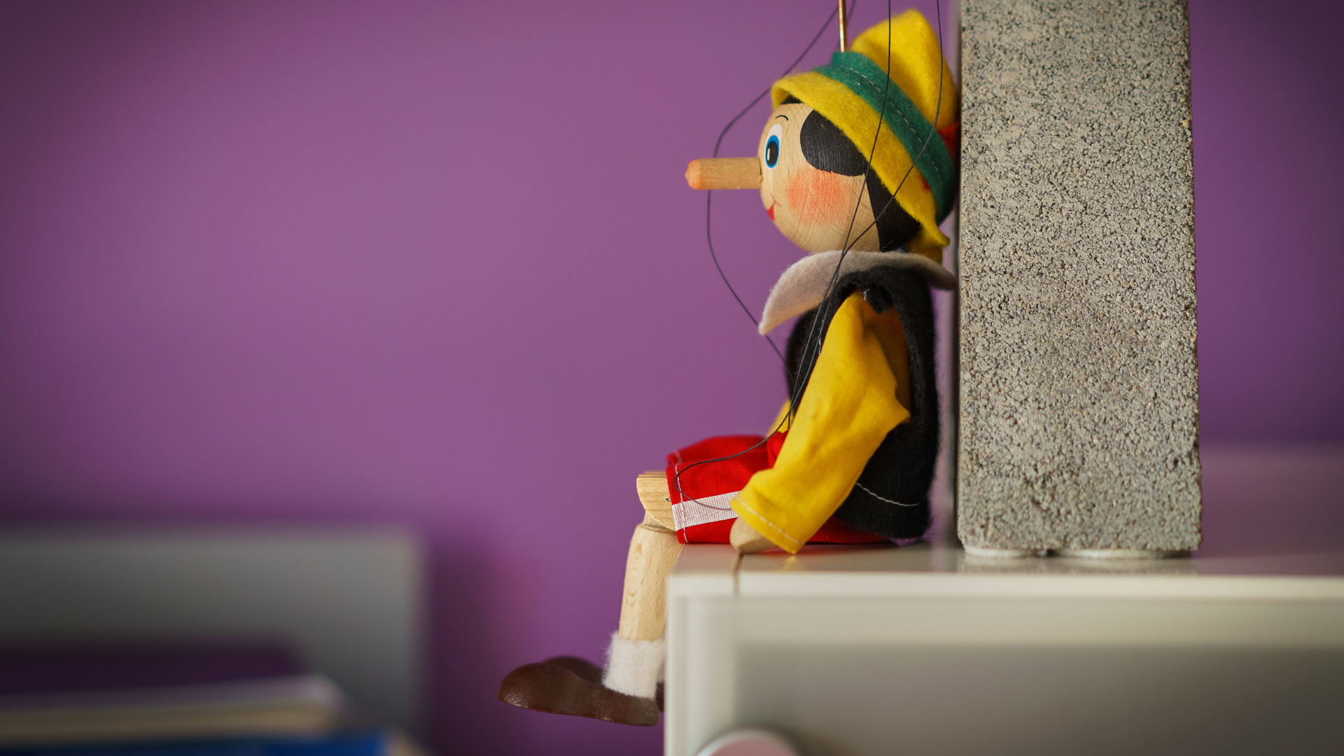 pinocchio toy sitting on a ledge and leaning with back on a wall