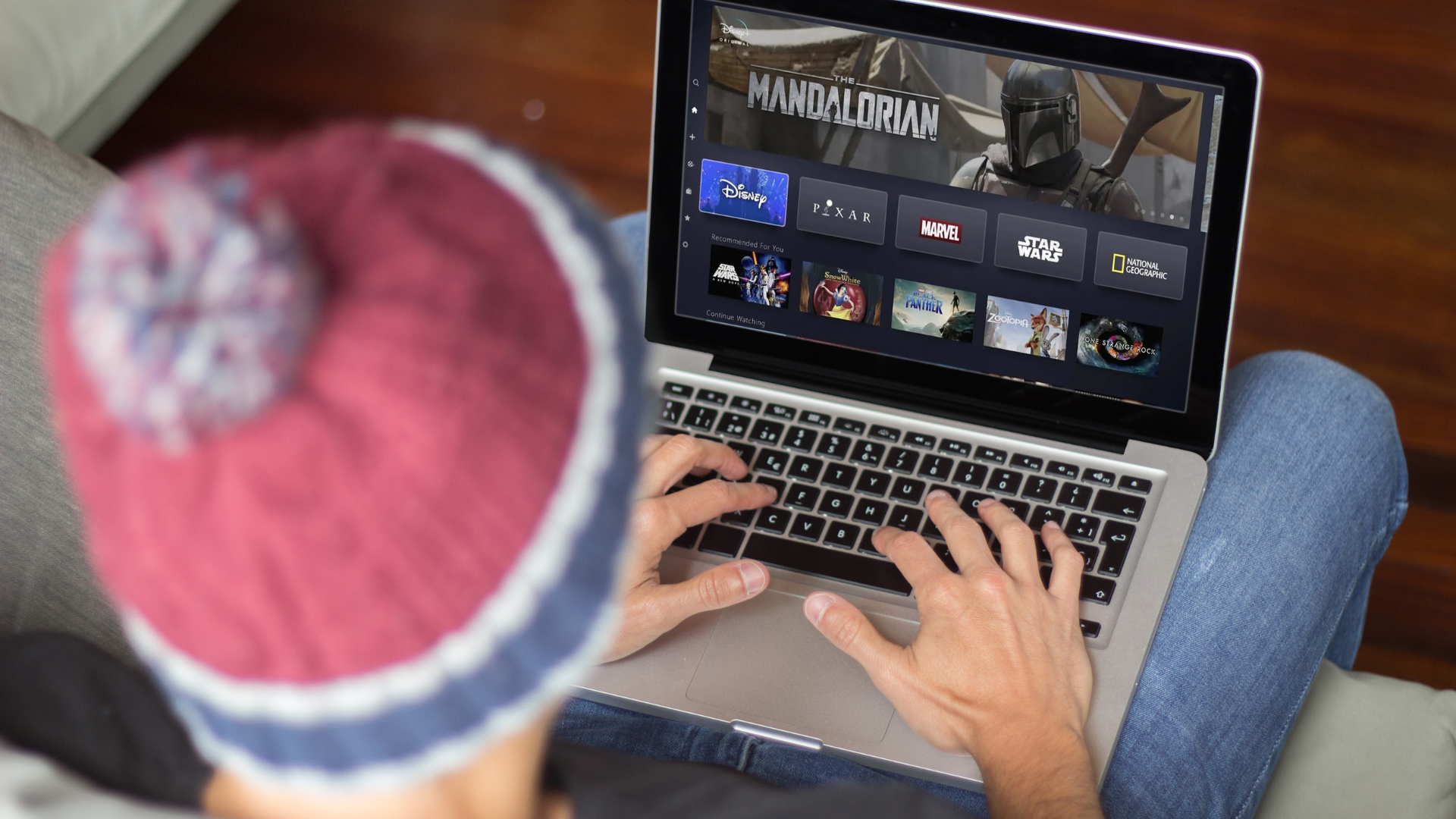 Man in hat watching Mandalorian Disney plus on laptop