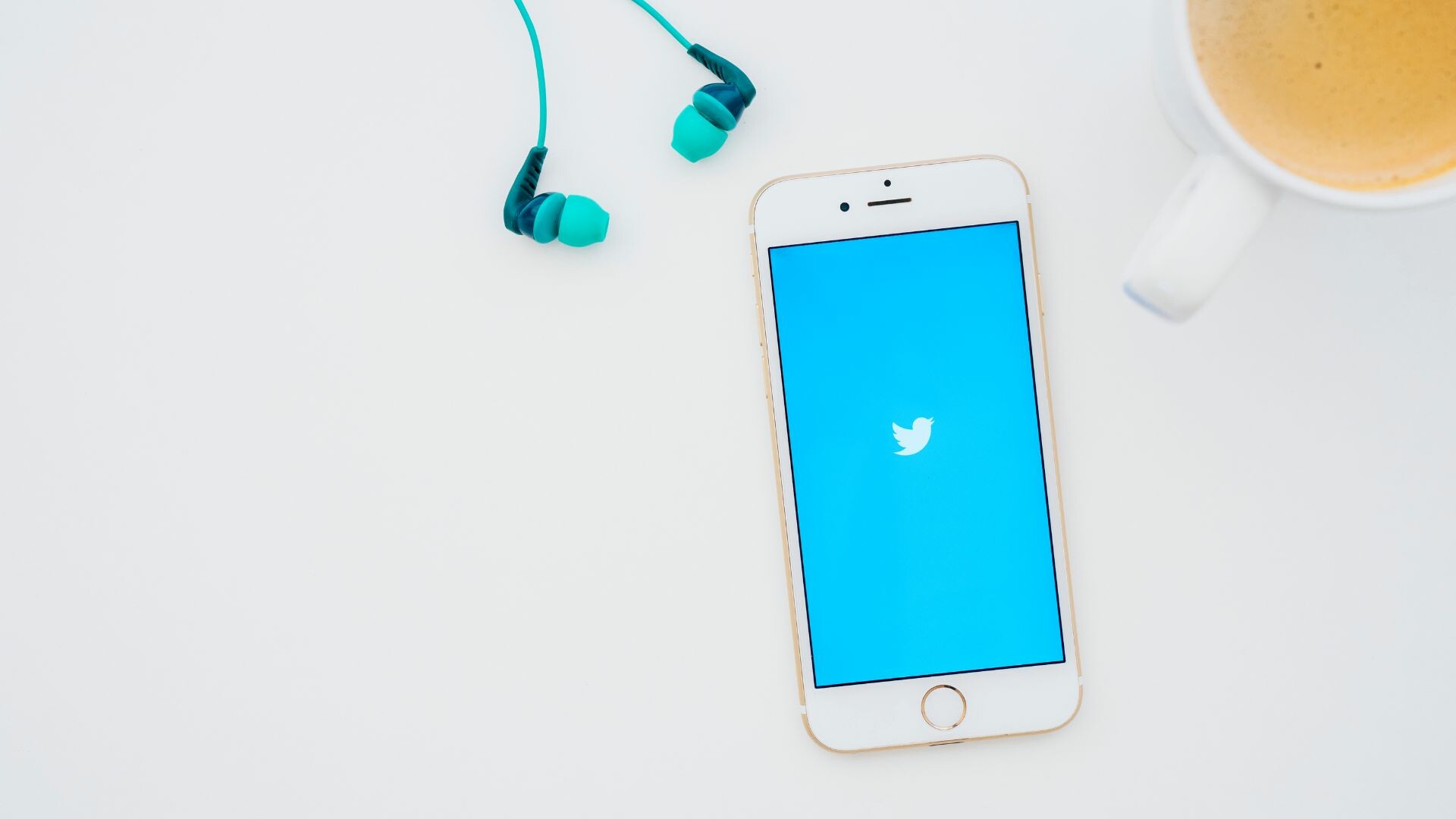 Twitter open on phone on table next to coffee and earphones