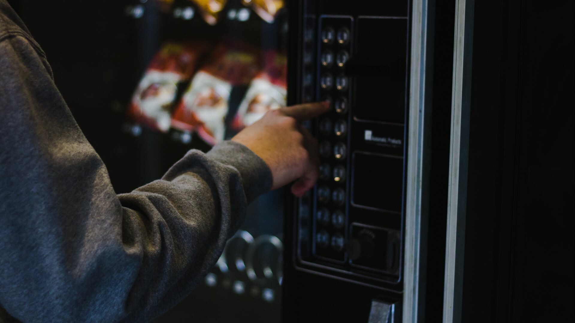 Person pushing a button on a vending machine.