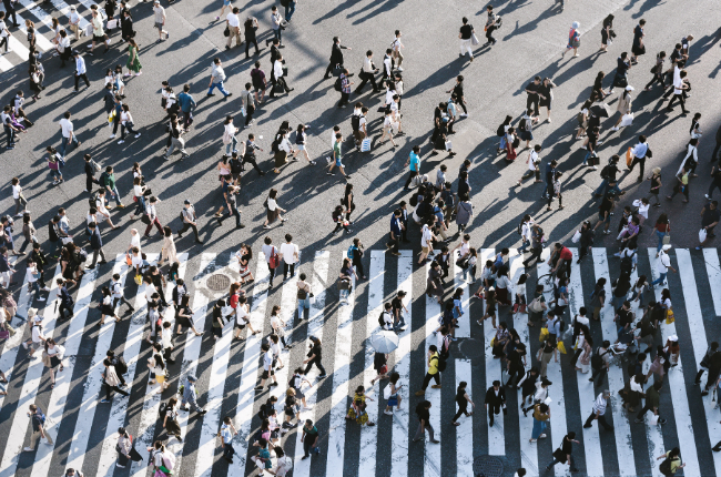 Crowd of people walking across a large, busy crosswalk