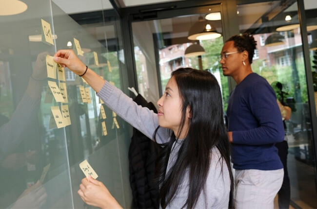 two people putting stickie notes on a board