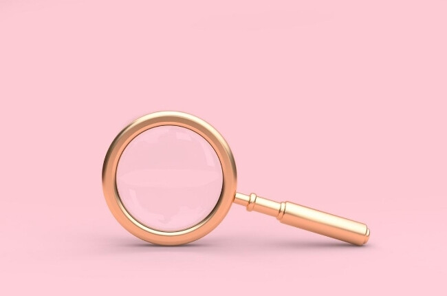 gold magnifying glass with a pink background