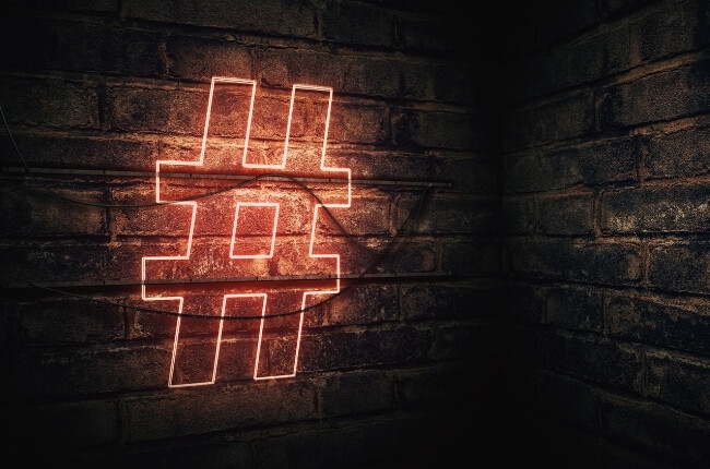 neon orange hashtag sign on a brick wall