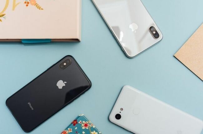 three iphones on a blue table