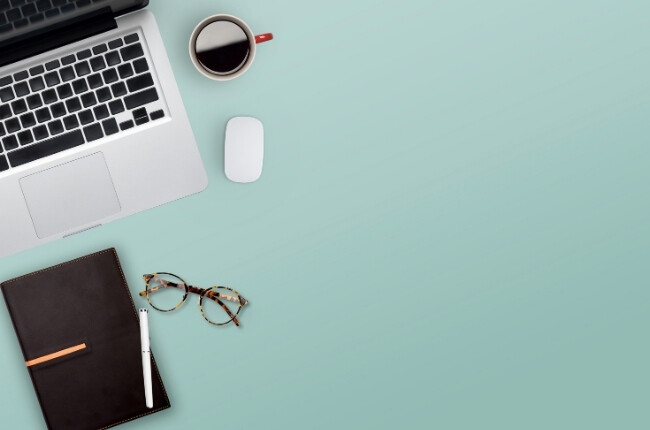 blue desk with laptop, notebook and glasses