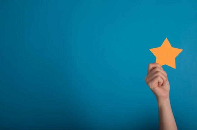 person holding a gold star against a blue backgound