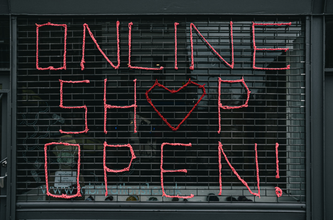 Red sign "Online Shop Open" on gate