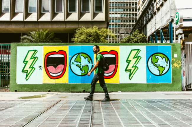 Person walking in front of wall with art 