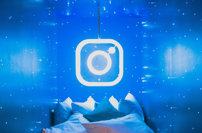 Neon light of Instagram logo in blue room