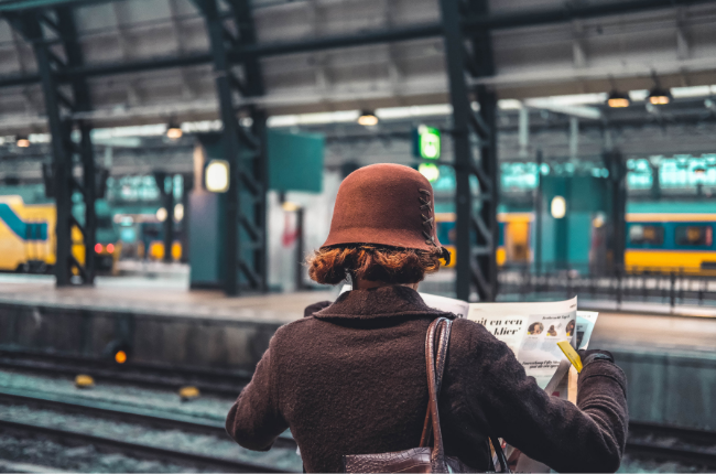 Person reading newspaper at station