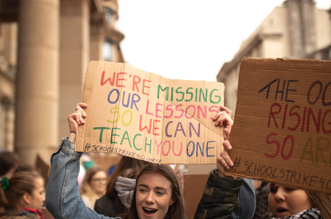 Young person holding sigh "We're missing our lessons so we can teach you one"