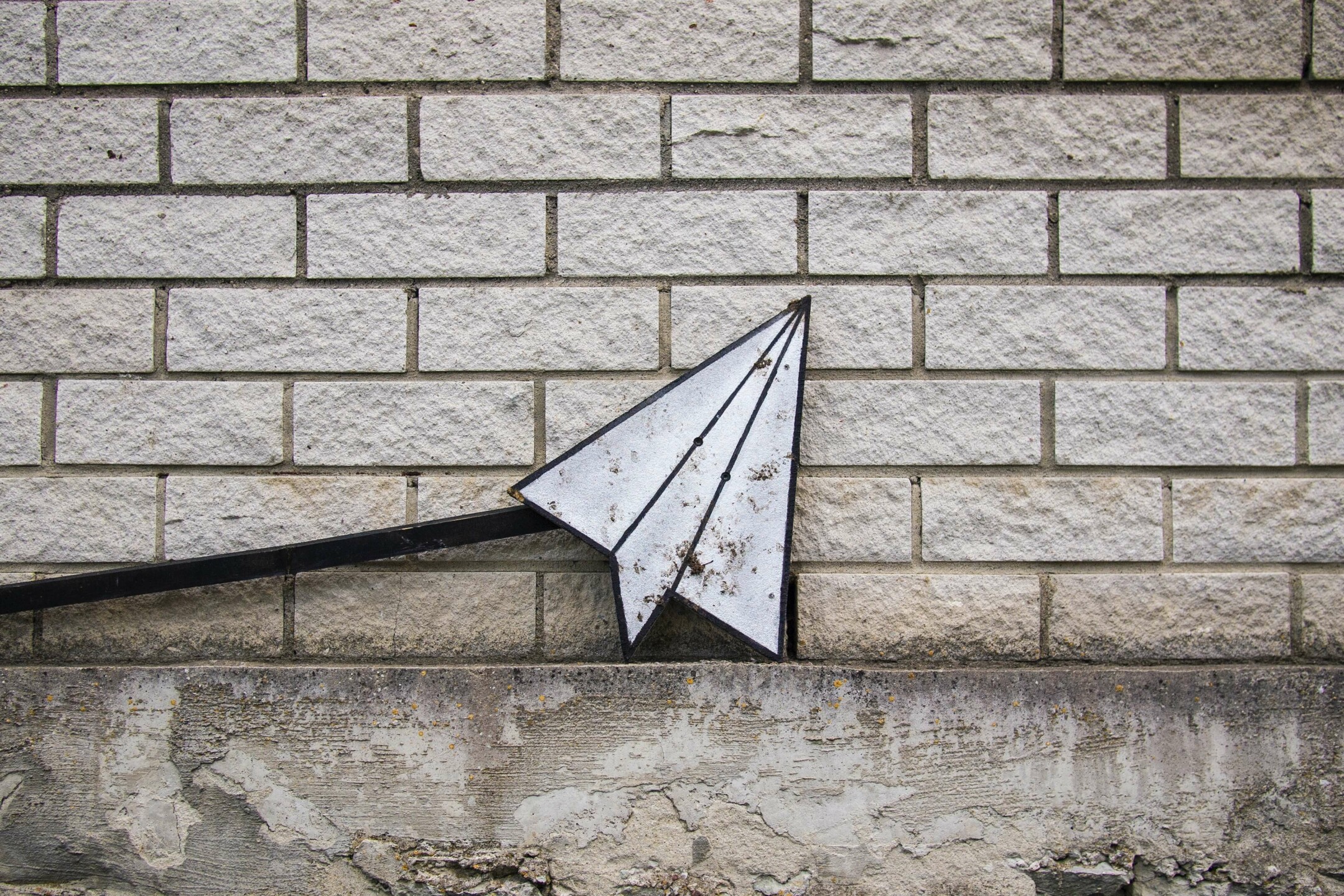 paper airplane sign on brick wall