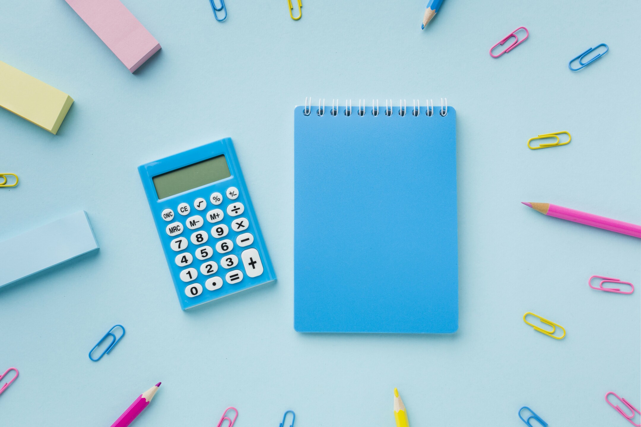 blue notepad and calculator with office supplies